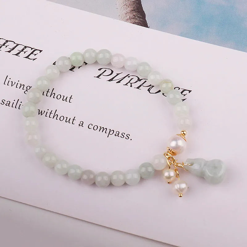 Close-up of a women's jade bracelet with a gourd motif, emerald jade insets, and pearl accents.