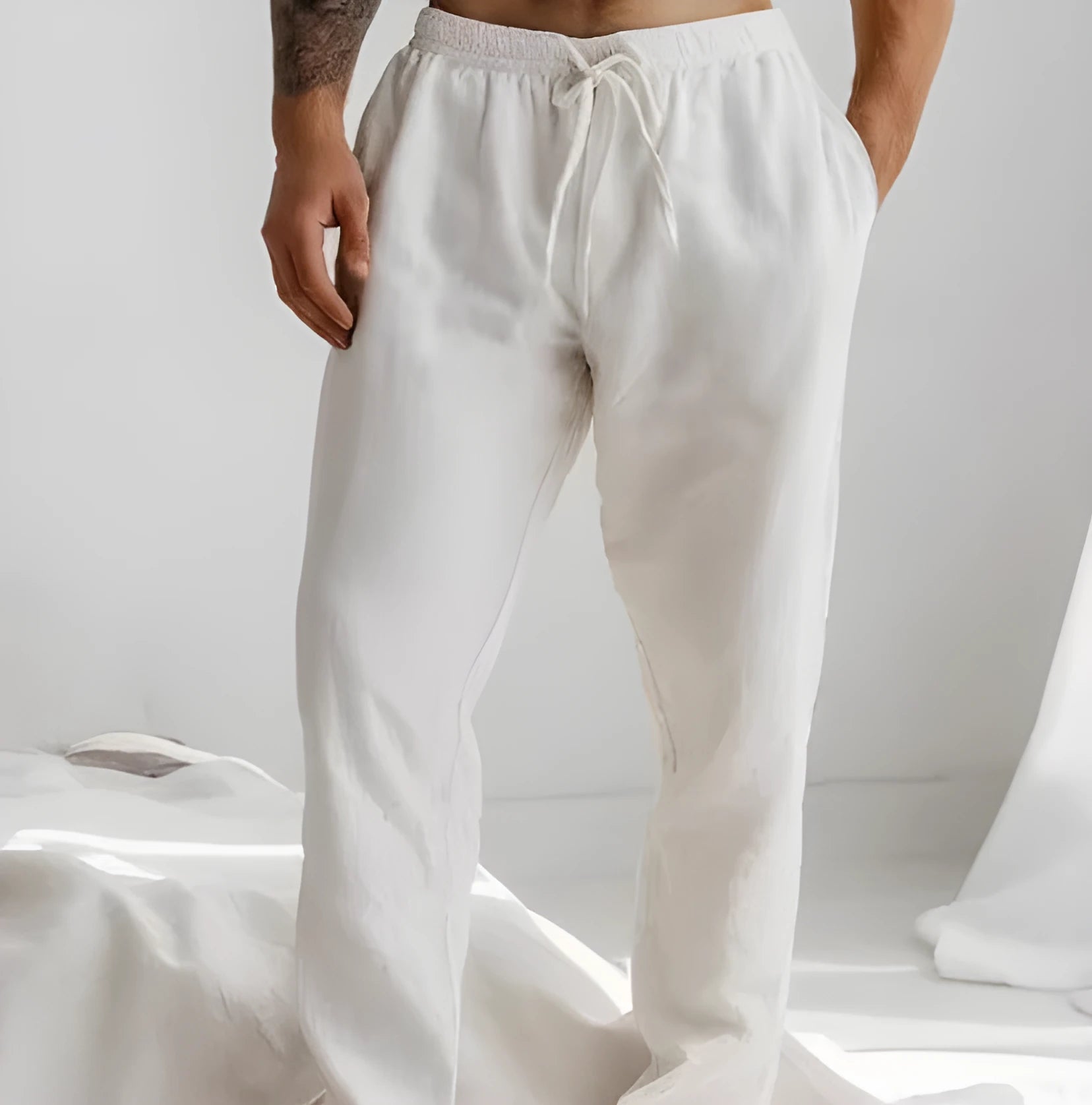 Man wearing light grey cotton-linen summer trousers with an elastic waist and straight leg fit.