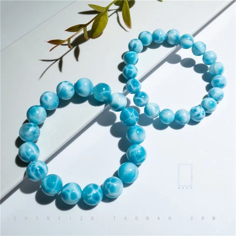 Blue handcrafted bodhi bracelet with sea-pattern crystal stones and pearl accents on a neutral background.