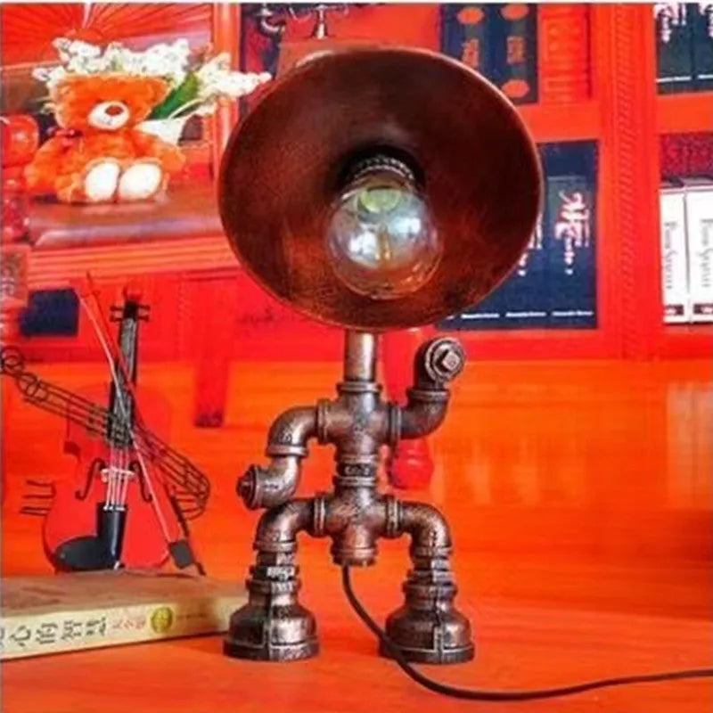 Industrial retro style table lamp made from iron pipes with a robot figure detail, in a vintage finish.
