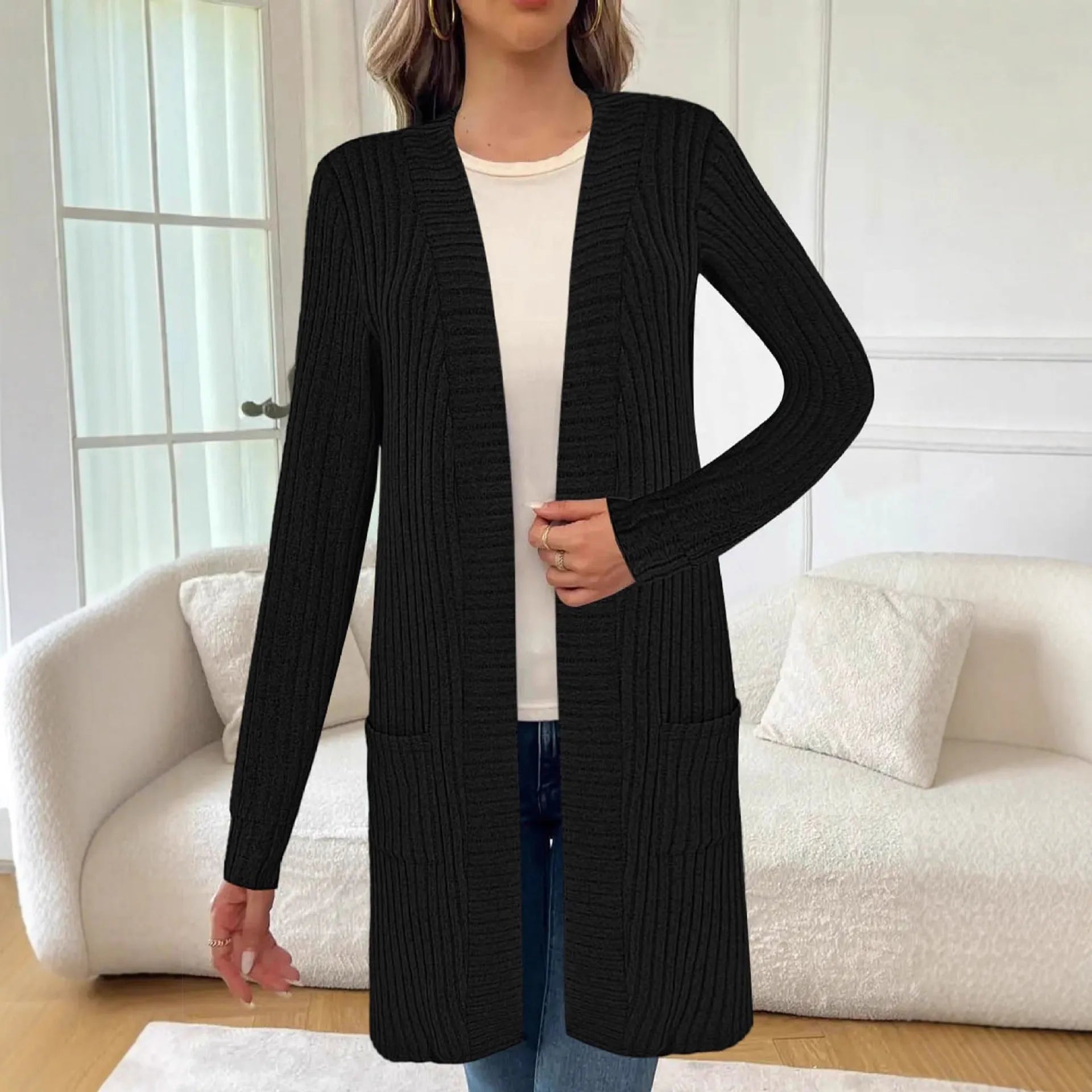Woman wearing a loose fit, long sleeve, grey knitted cardigan jacket with patch pockets.
