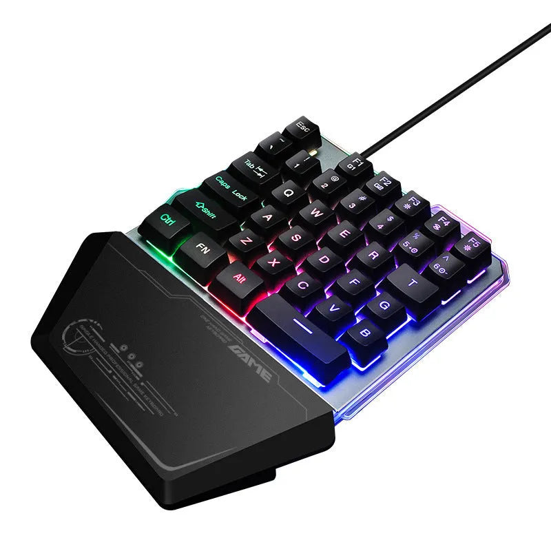 Black one-handed robotic gaming keyboard with RGB backlit keys on a desk.