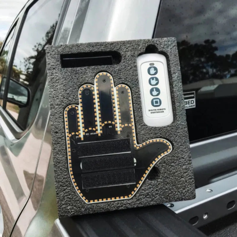 Black plastic LED car gesture light showing illuminated middle finger sign on dashboard