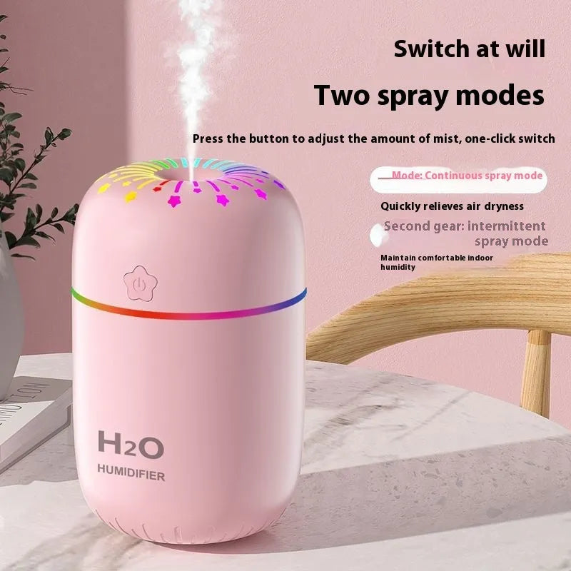 White USB mini humidifier with water tank on desk next to laptop