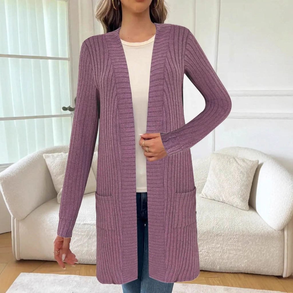 Woman wearing a loose fit, long sleeve, grey knitted cardigan jacket with patch pockets.