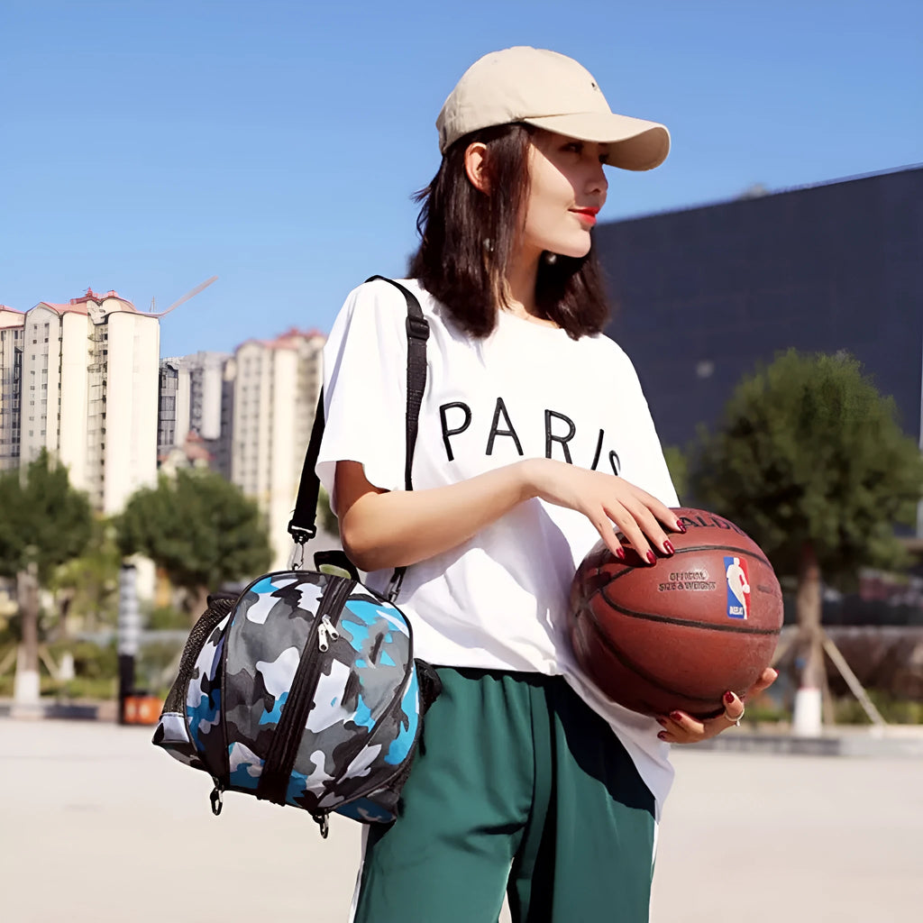 Black Oxford cloth basketball bag with one shoulder strap, shown next to a basketball.