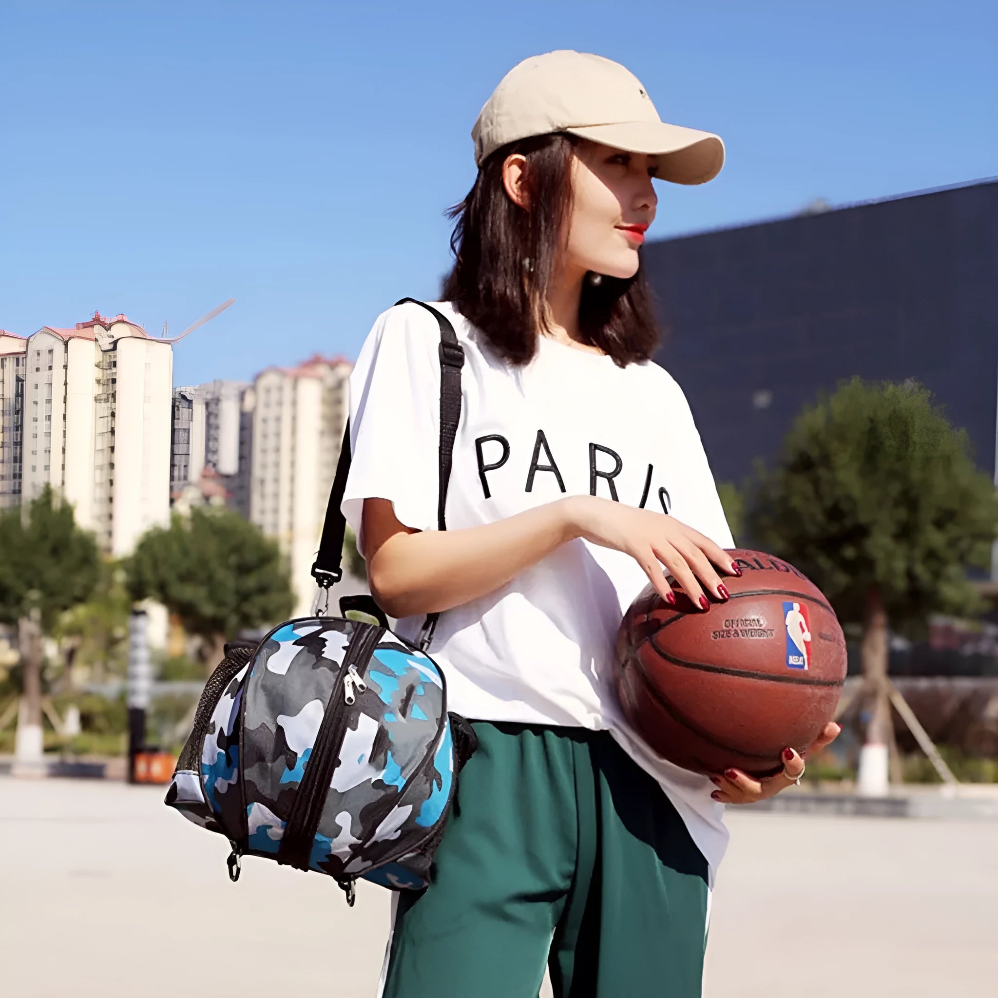 Black Oxford cloth basketball bag with one shoulder strap, shown next to a basketball.