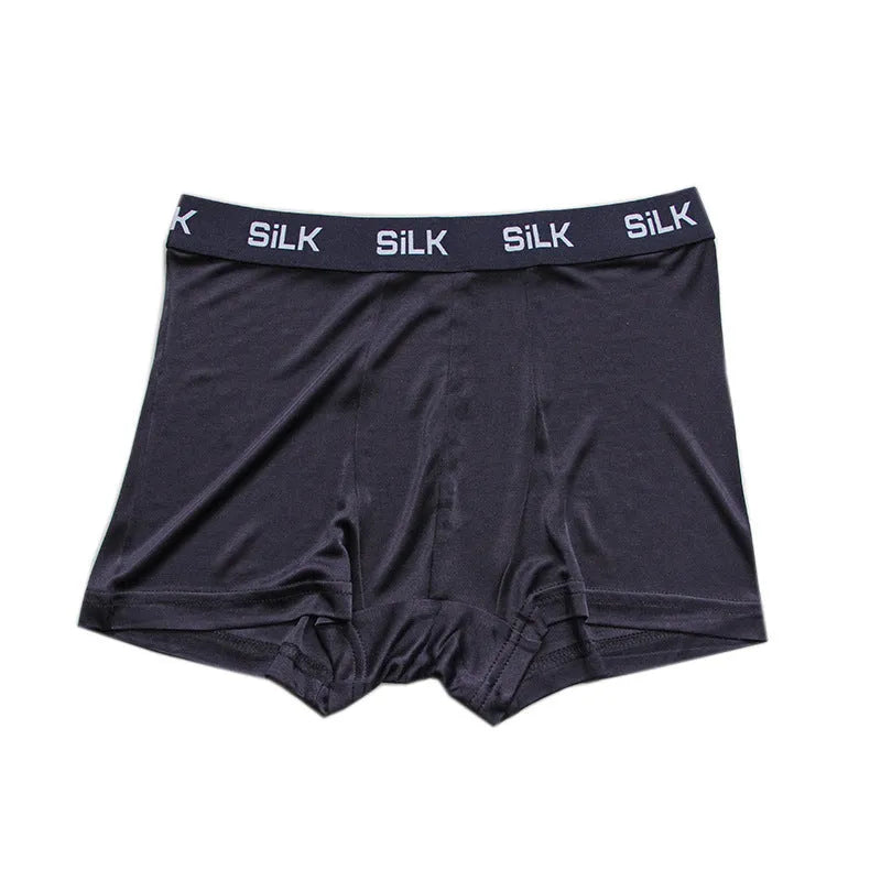 Man wearing loose-fitting mid-waist silk shorts in navy blue, silver grey, or skin colour.