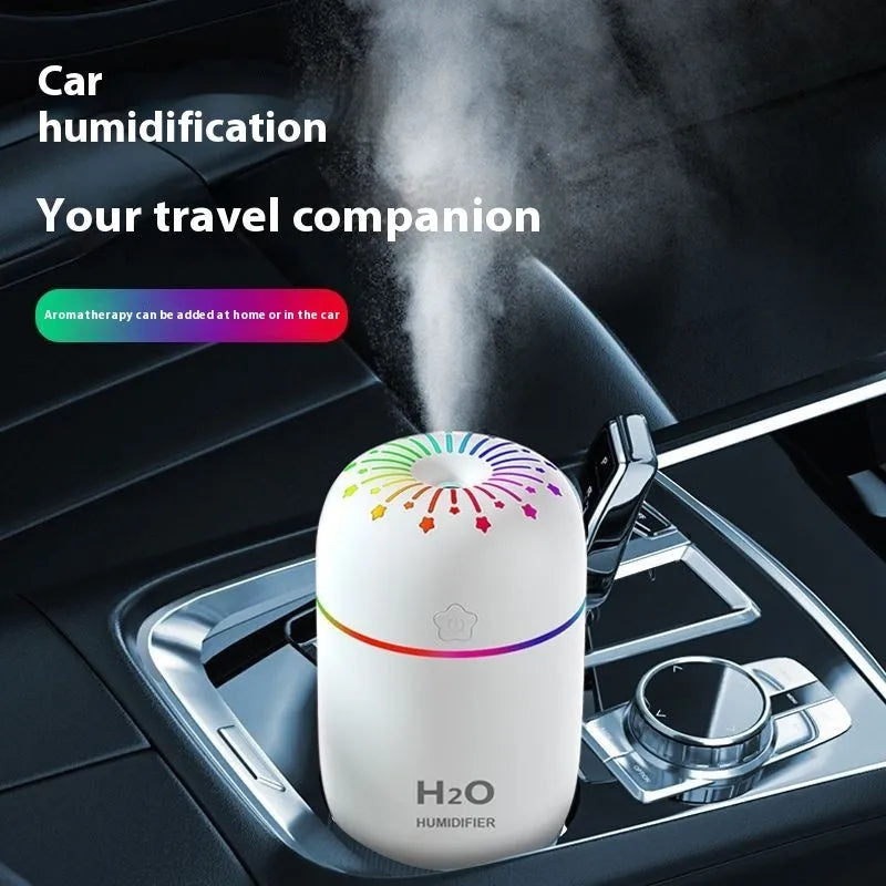 White USB mini humidifier with water tank on desk next to laptop