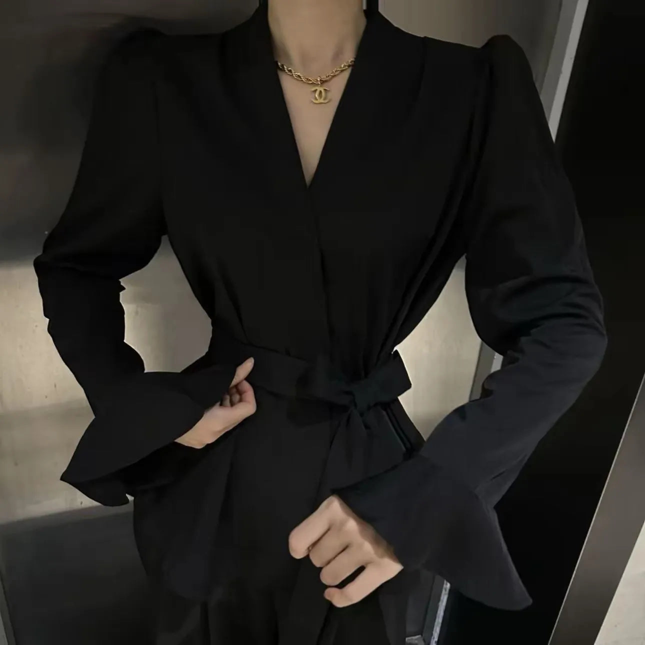 A woman's French-style black shirt with an irregular collar, long bell sleeves, and a tied front closure.