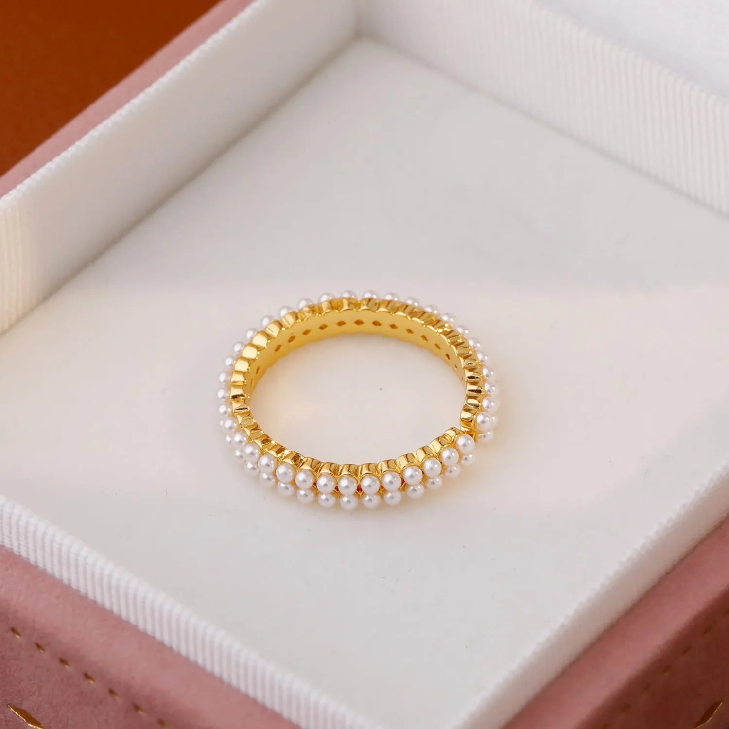Gold geometric open ring for women with a pearl centre on a white background.