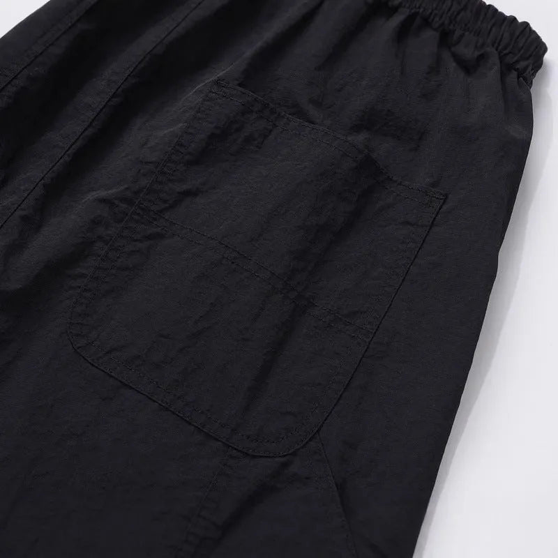 Black baggy paratrooper pants with an elastic drawstring waistband on a mannequin.