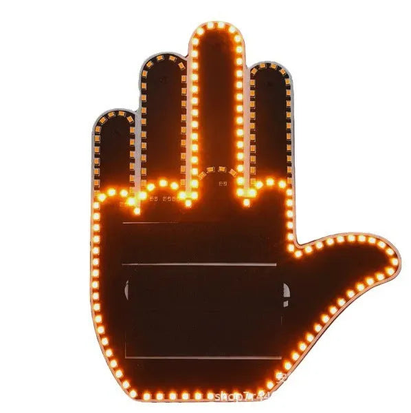 Black plastic LED car gesture light showing illuminated middle finger sign on dashboard