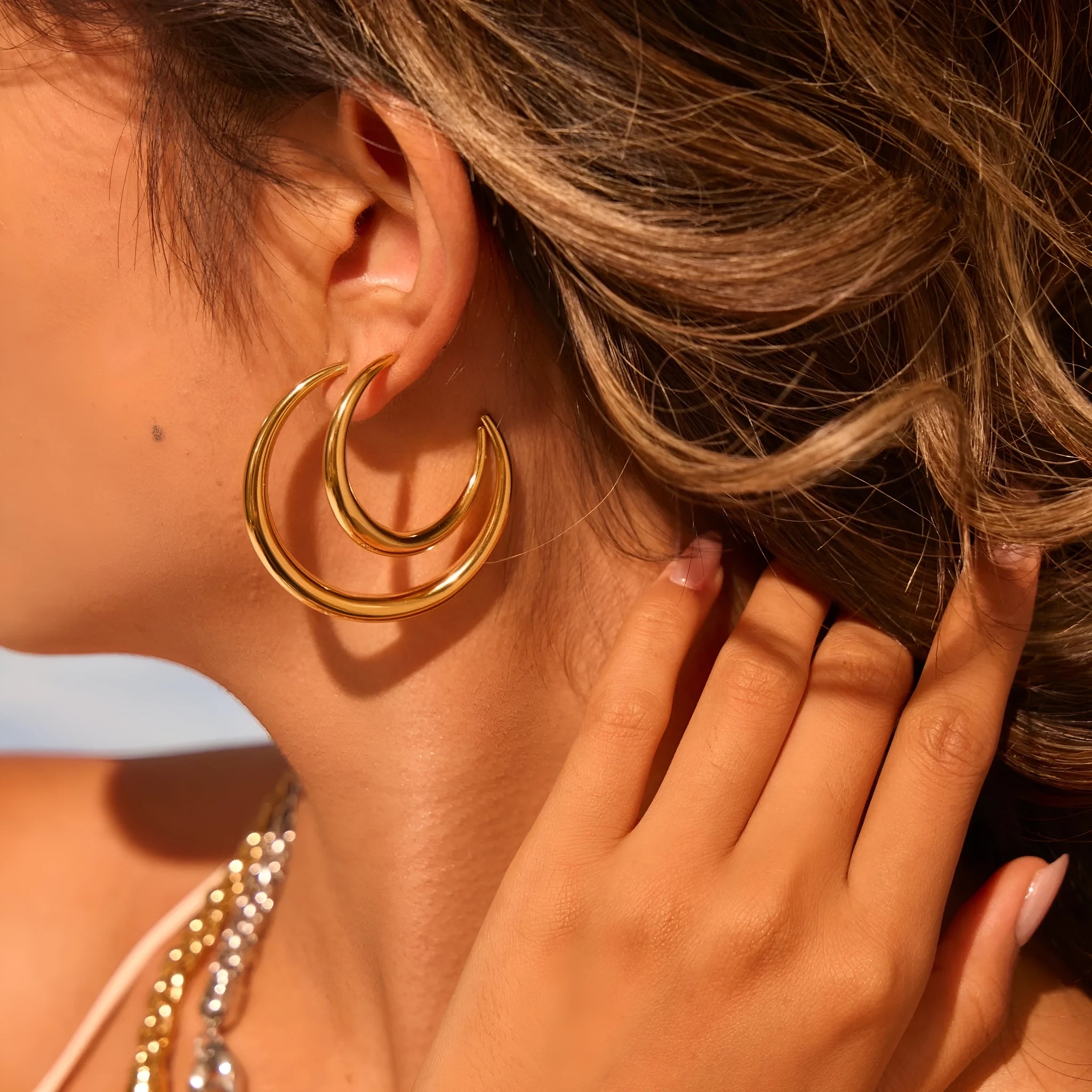 A pair of simple round titanium steel hoop earrings for women, shown in gold and steel finishes.