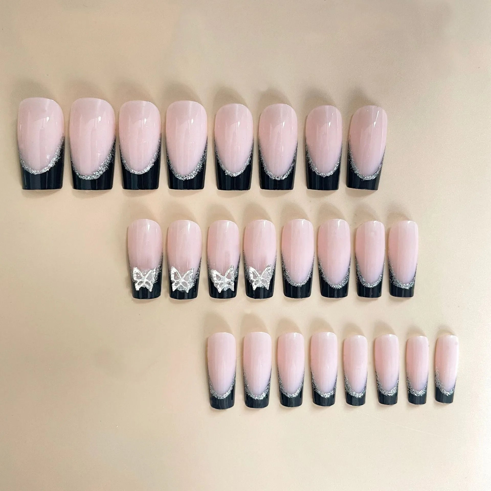 Black French style false nails with glittering butterfly decoration on medium length press-on nails.