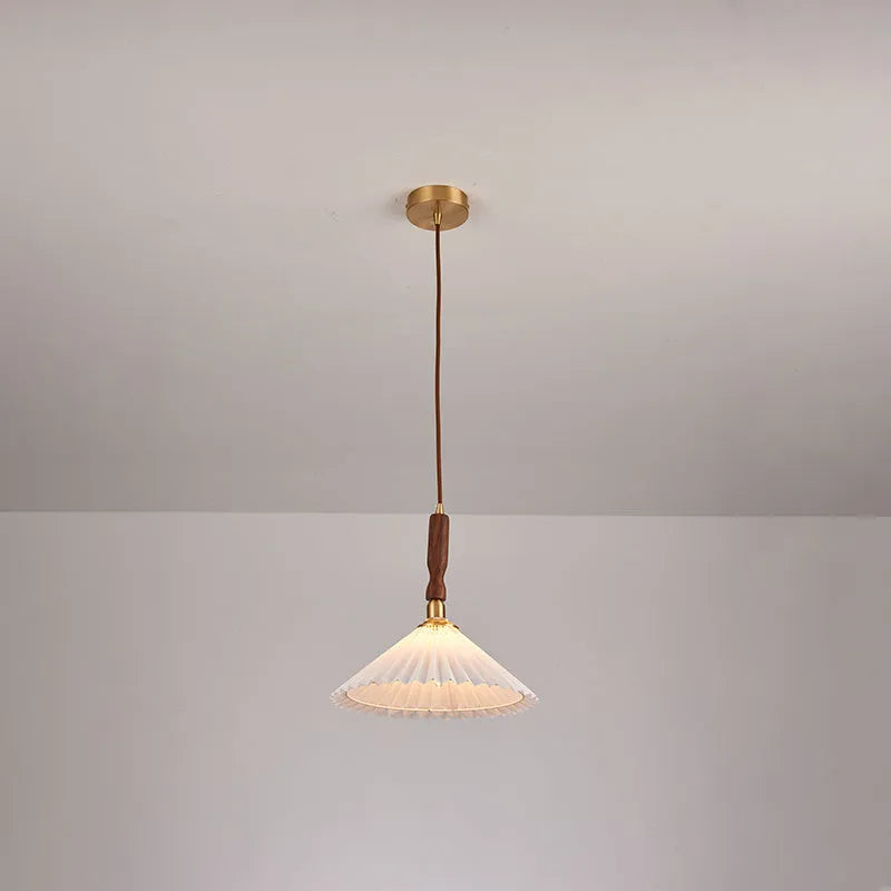 Retro wooden wall lamp with fabric shade in walnut finish mounted beside a bed.