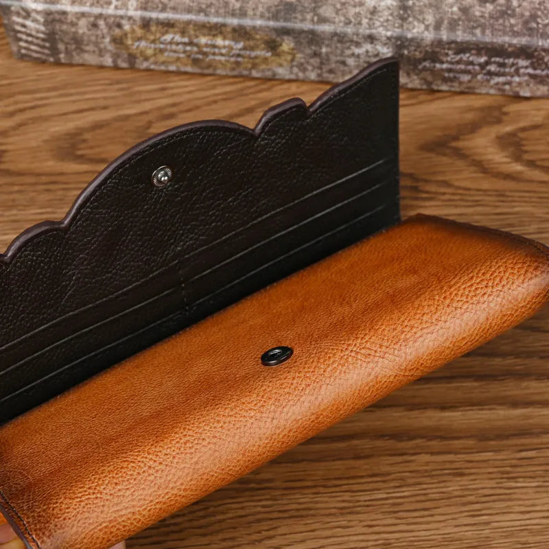 Women's brown tri-fold leather wallet with embossed floral pattern, shown open to reveal compartments.