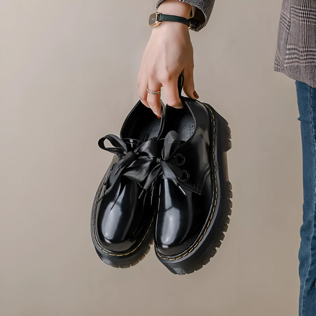 Black and white thick soled women's lace-up shoes with cross straps on a superfine fibre upper.
