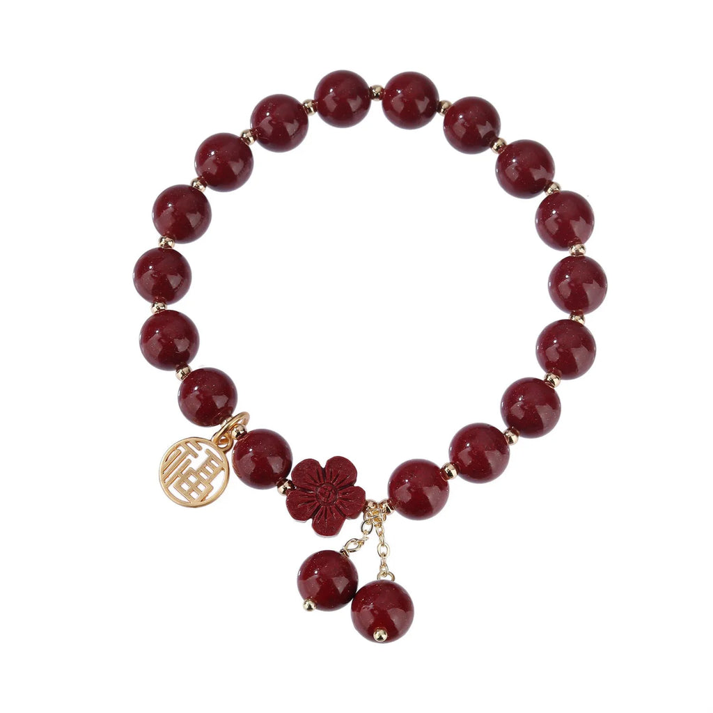 Women's handmade cinnabar bracelet with fu character charm and tassel detail in purple gold sand finish