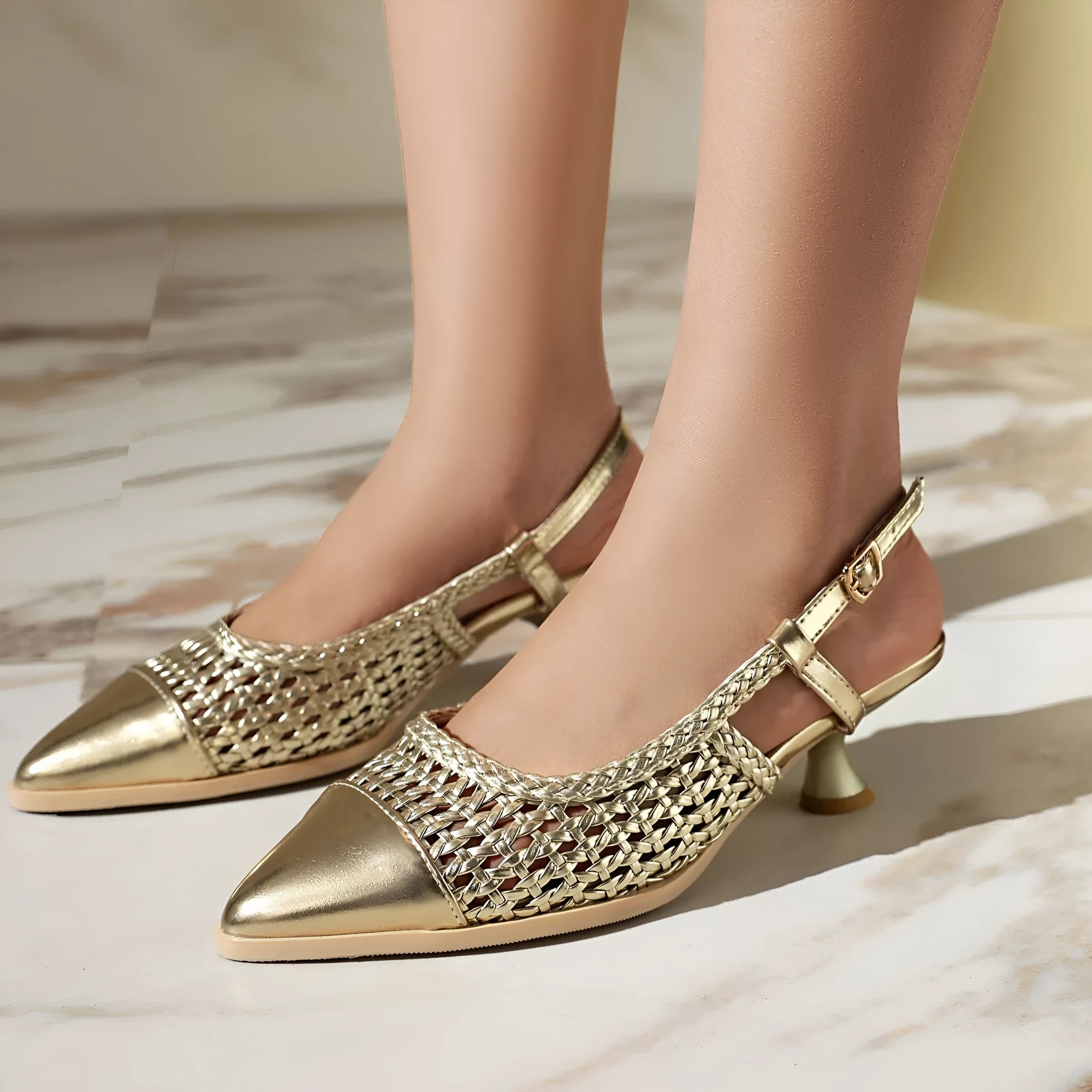 Gold women's sandals with a cat heel and ankle buckle fastening on a white background.