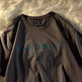 Loose fit black cotton t-shirt with white letter print on a mannequin, front view.