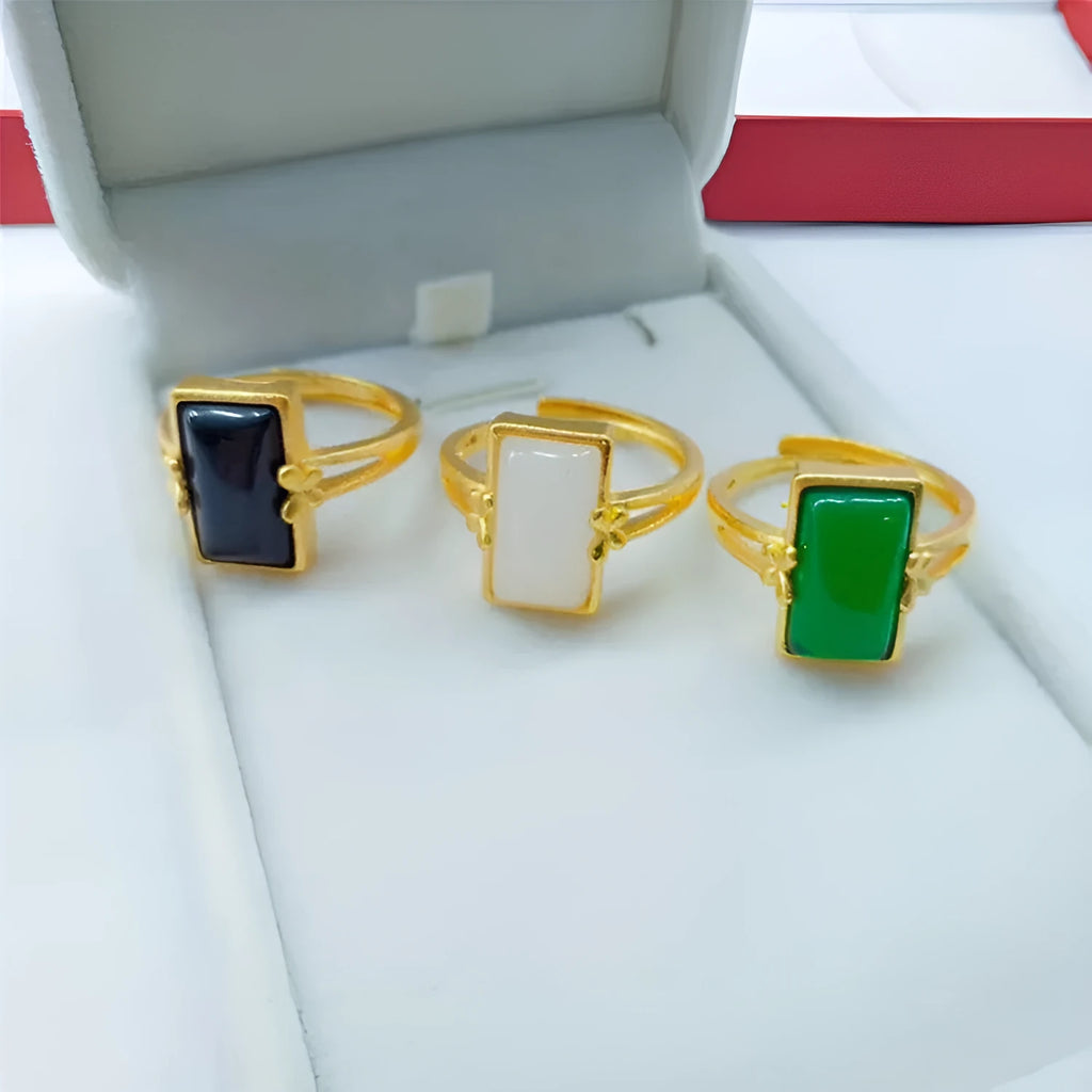 Gold-plated adjustable brass ring with a central inlaid gemstone, shown in black, green, and white colour options.
