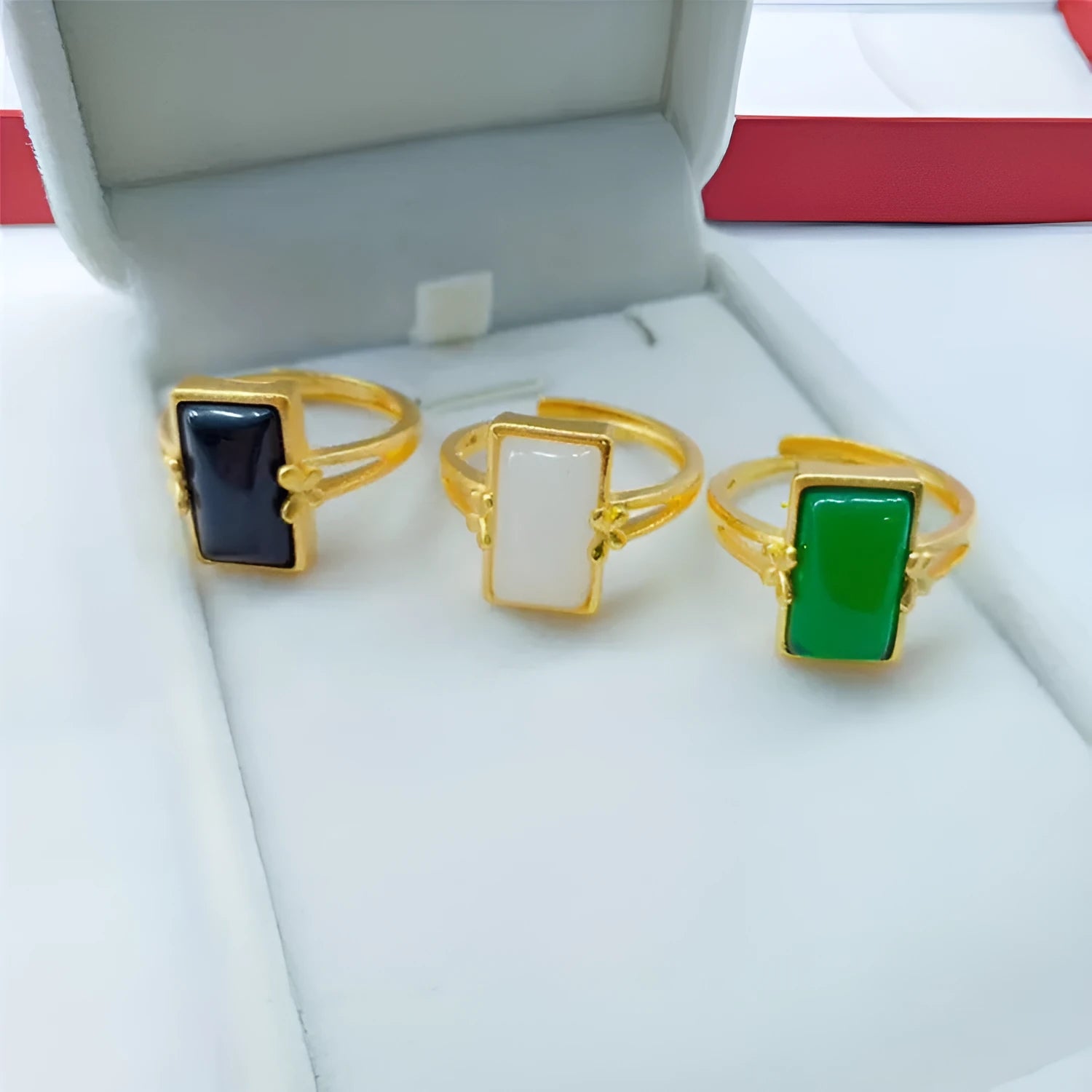 Gold-plated adjustable brass ring with a central inlaid gemstone, shown in black, green, and white colour options.