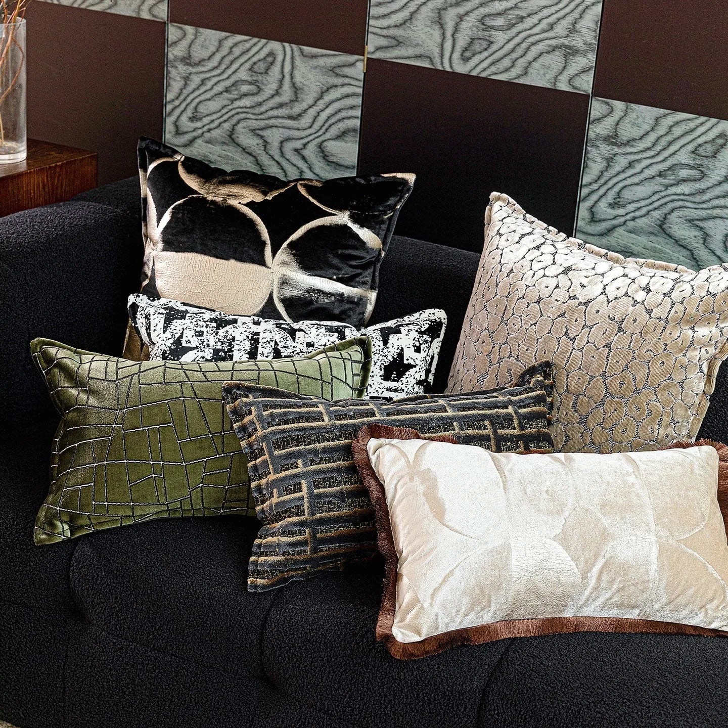 Black and gold abstract patterned flannel decorative cushion on a grey sofa.