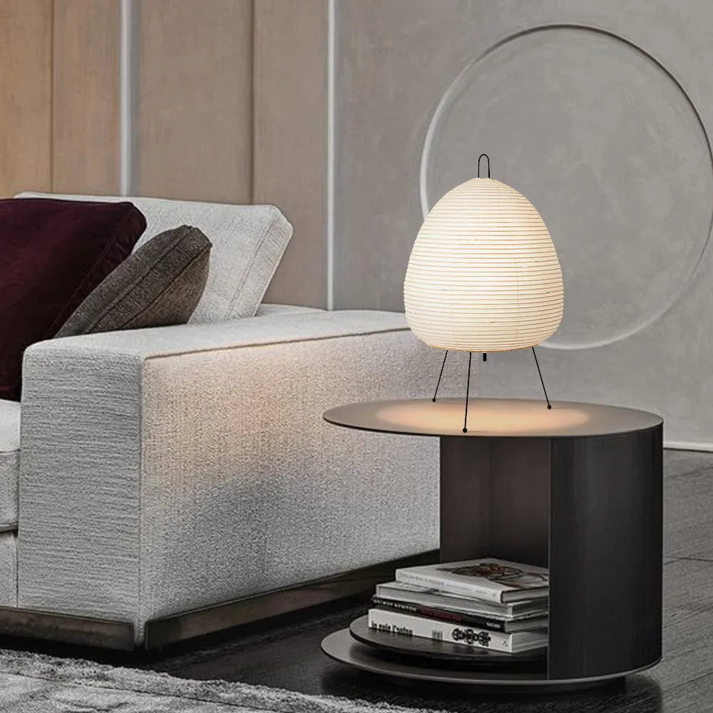 Japanese style handmade rice paper table lamp with an aluminium base on a wooden table.