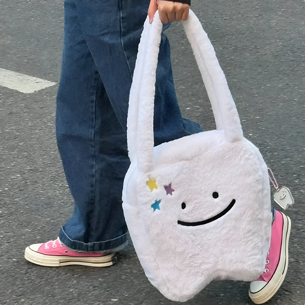 White plush tote bag with tooth decoration and shoulder strap showing zip opening