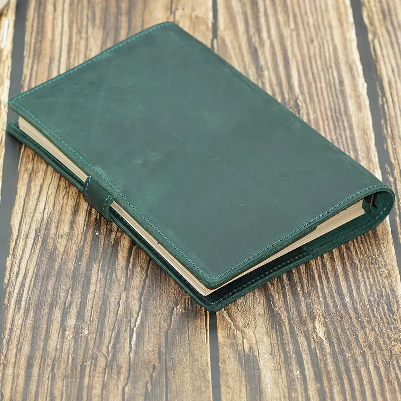 A5 handmade cowhide leather loose-leaf notebook in black with 100 sheets of kraft paper on a desk