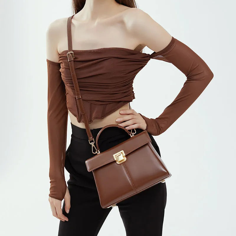 Black leather women's shoulder bag with vachette clasp showing horizontal square shape and adjustable strap