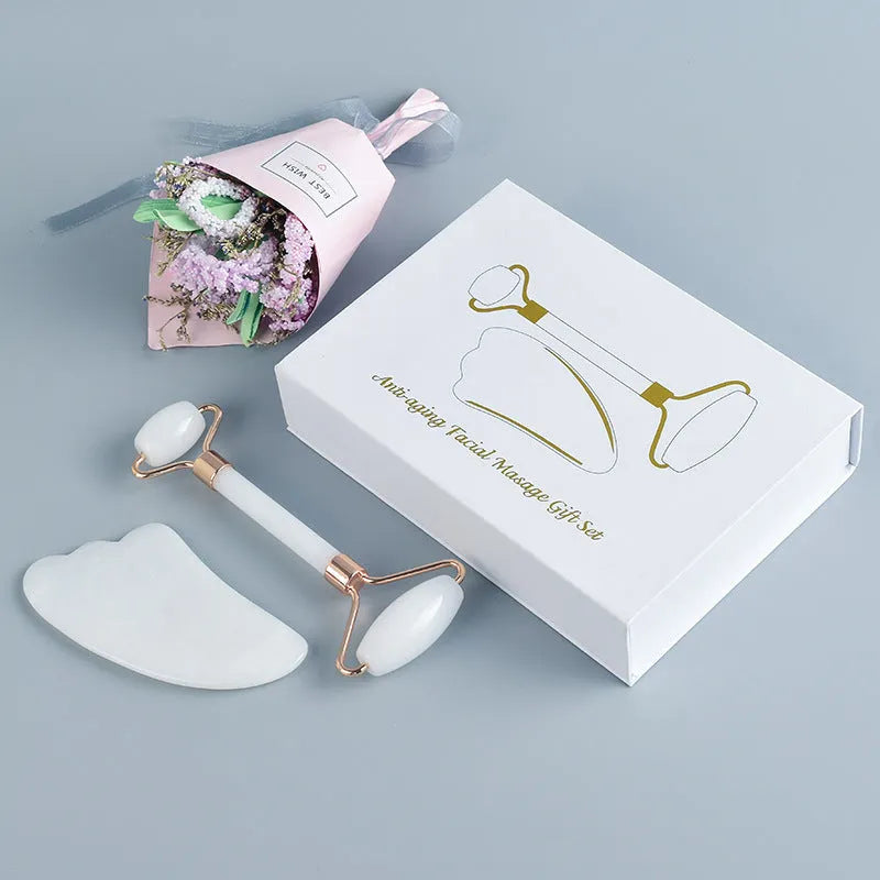 White jade facial roller and gua sha scraping tool set on a storage board.