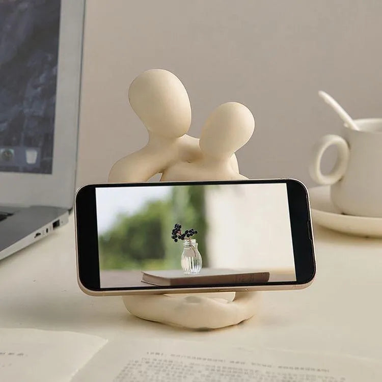 Modern minimalist loving couple resin statue in milky white or gold finish on a desk.