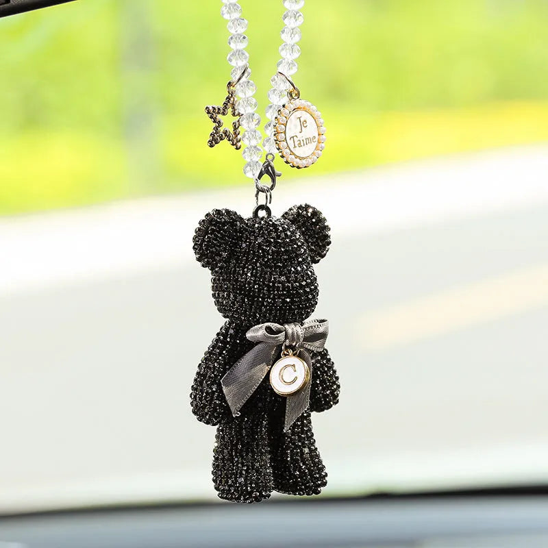 Close-up of a black Violent Bear-shaped car pendant with sparkling rhinestones, hanging from a rearview mirror.