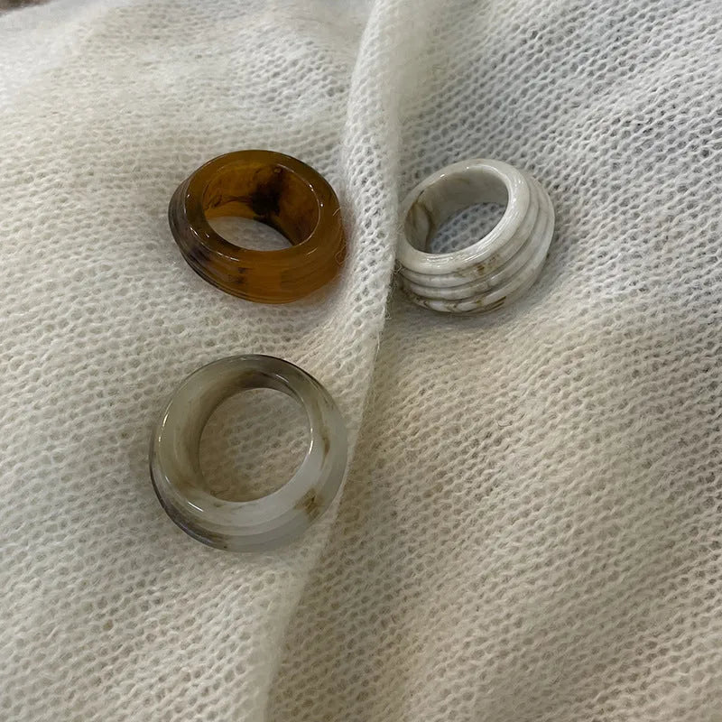 Chinese style irregular wide geometric resin ring in brown or white on display.
