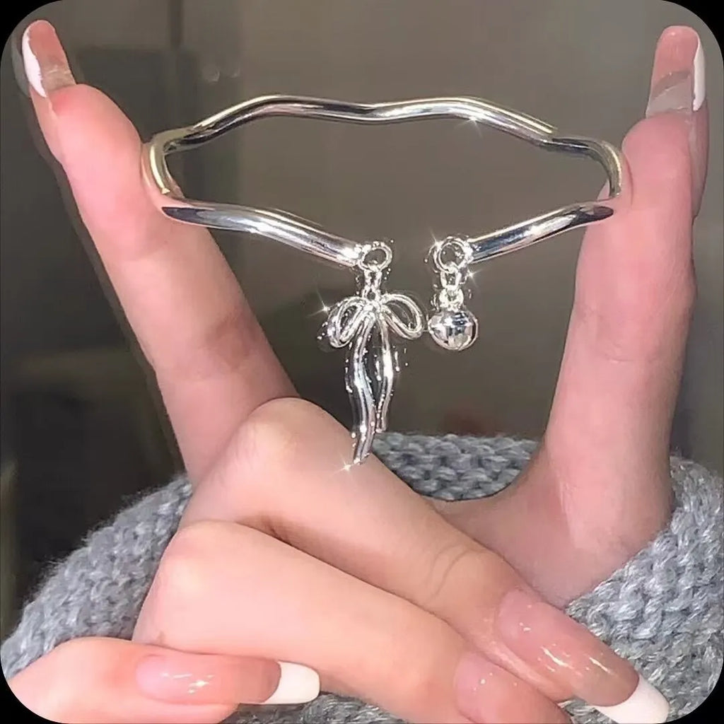 Silver adjustable women's bracelet with a bow bell charm on a zinc alloy bangle.