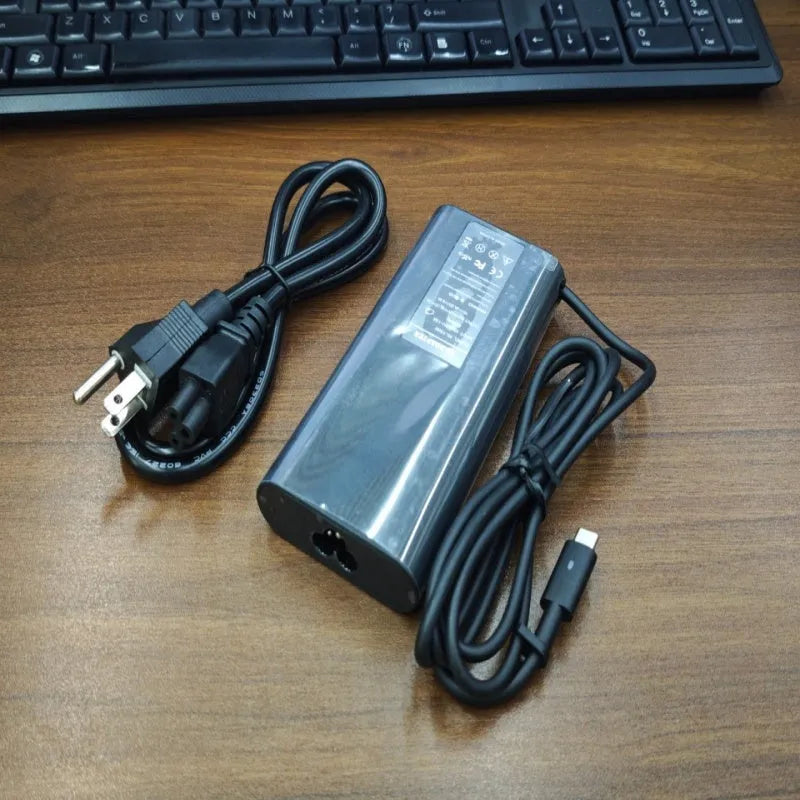 Black 65W Type-C laptop power adapter with multiple international plug heads on a white background.