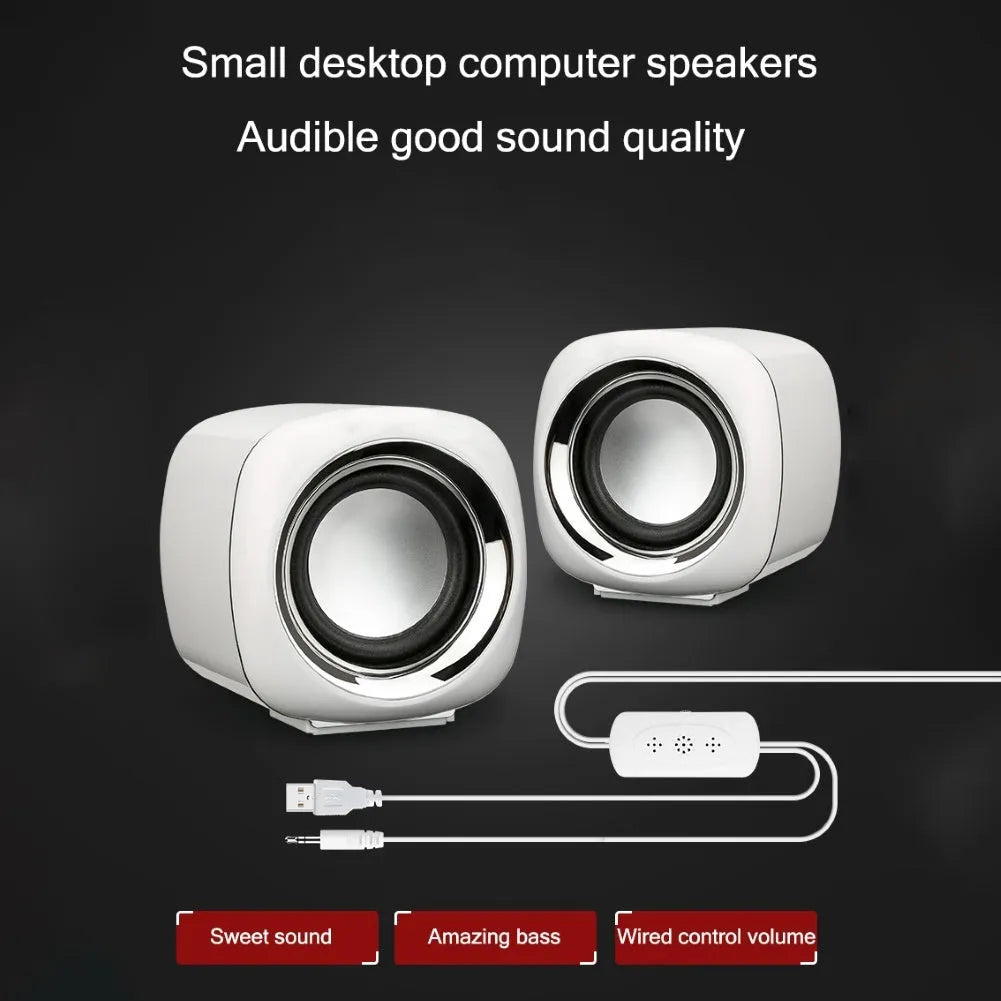 A pair of compact black or white wired desktop computer speakers with a volume scroll wheel.