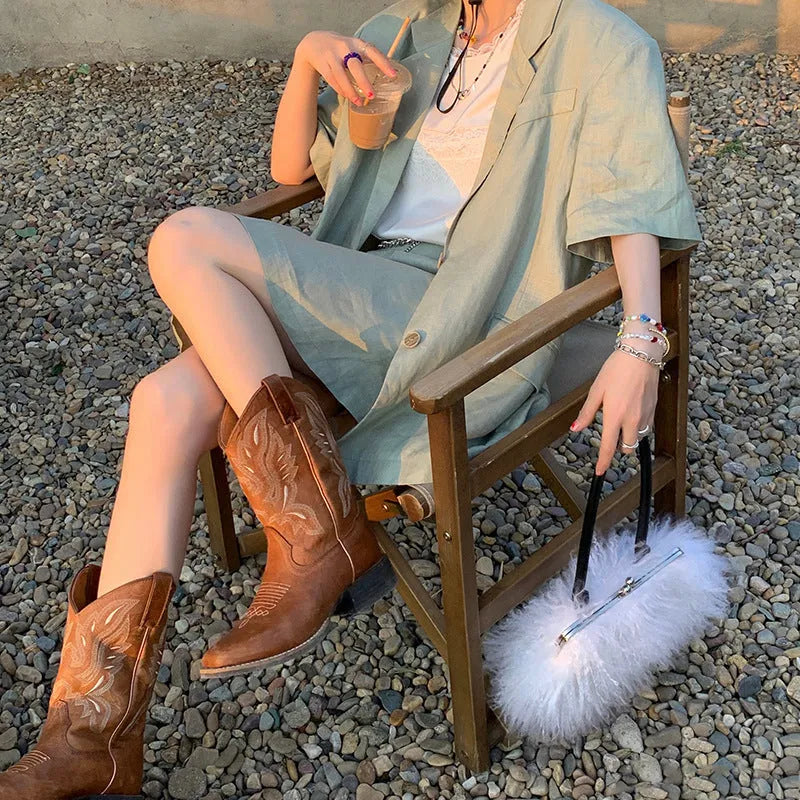 Brown women's mid-calf Martin boots with embroidered detail on the upper and a low square heel.