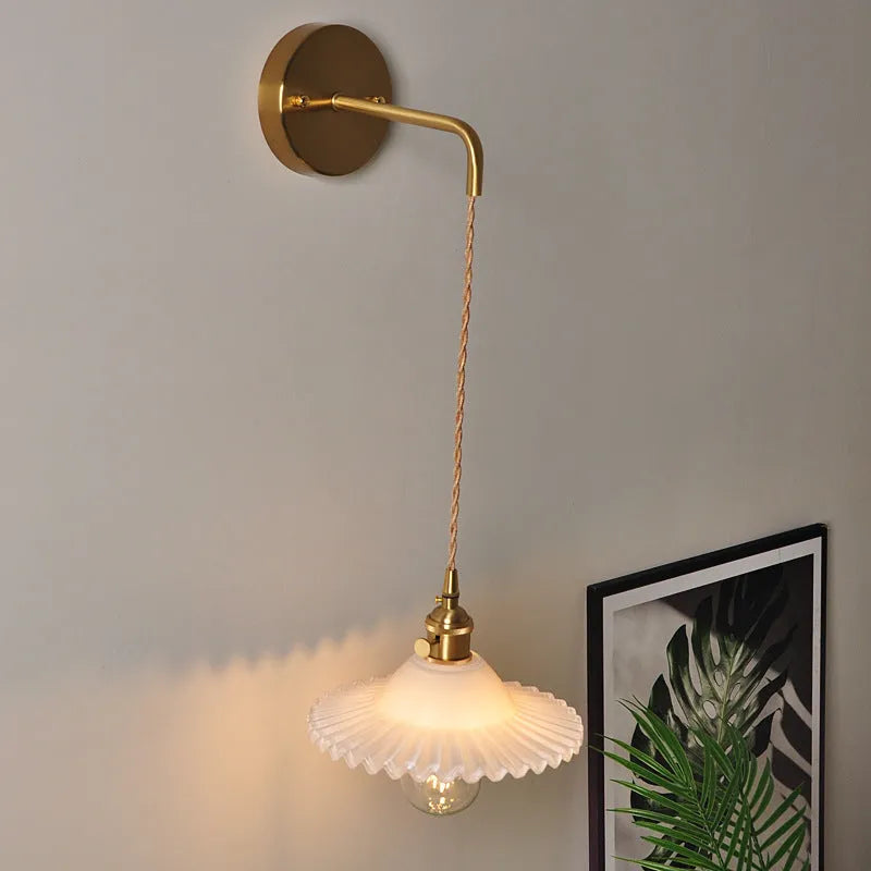 Brass lotus wall lamp with glass shade in six colour options on a wall