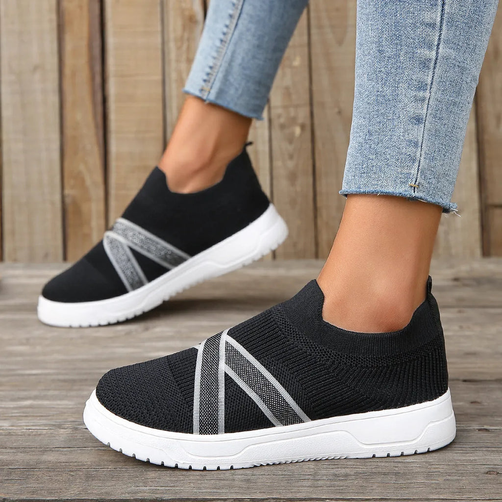 Black women's Flyknit mesh flat shoes with a tassel detail on the low-top upper and a flat rubber sole.