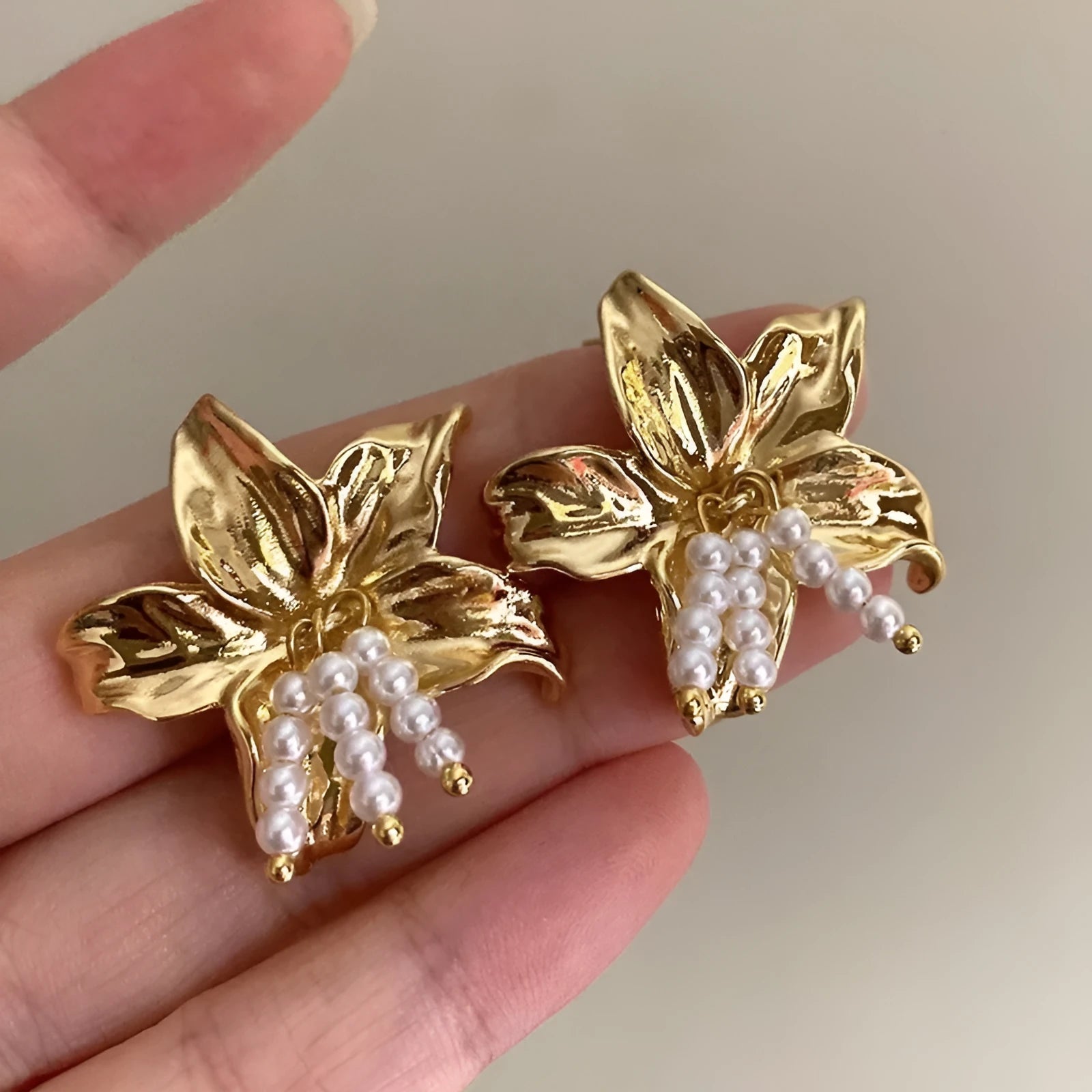 A pair of gold H1795 flower-shaped earrings for women with a Seiko-treated metal finish.