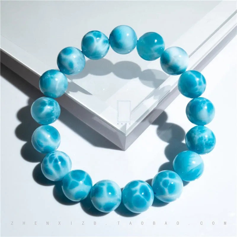 Blue handcrafted bodhi bracelet with sea-pattern crystal stones and pearl accents on a neutral background.