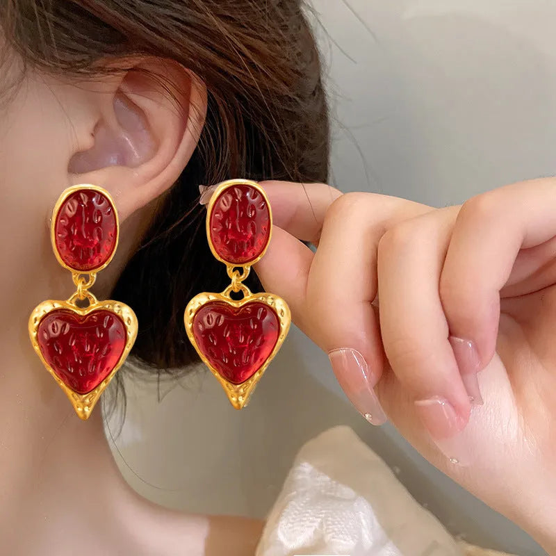 A pair of oval-shaped love heart stud earrings with a pleated surface, shown in one of four colour options.