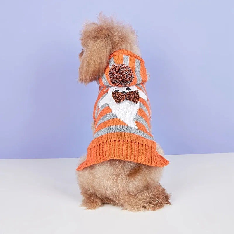 Orange knitted dog sweater with striped pattern, fur ball trim, and a hood for Halloween.