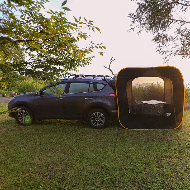 Black pop-up car tailgate camping tent unfolded next to a vehicle