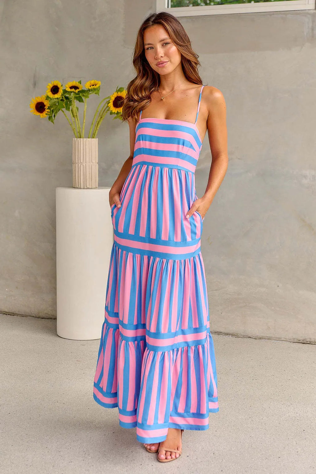 Women's striped backless summer dress with suspender straps and side pockets in a blue colour.