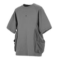 Man wearing a loose grey cotton T-shirt with large side pockets on a casual background.