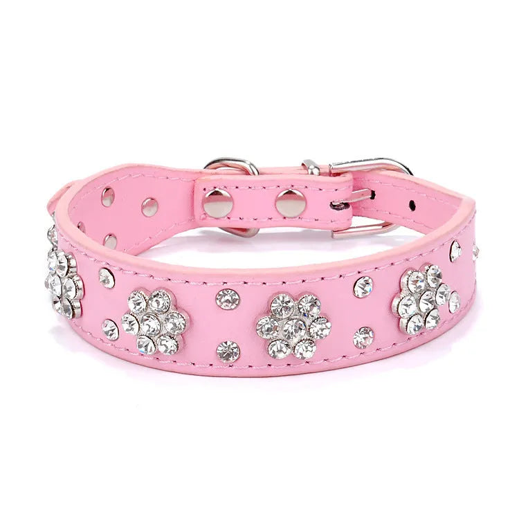 A pink PU leather dog collar studded with silver rhinestone flowers and a metal D-ring.